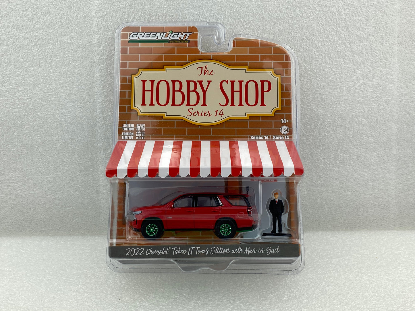 GreenLight Green Machine 1:64 The Hobby Shop Series 14 - 2022 Chevrolet Tahoe LT Texas Edition with Man in Suit 97140-F
